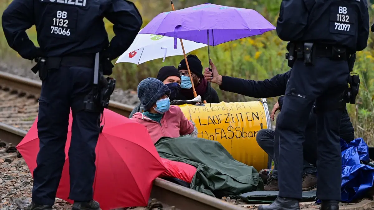 19. September 2022: Mitglieder der Gruppe „Unfreiwillige Feuerwehr“ blockieren eine Gleisverbindung für den Transport von Braunkohle zum Kraftwerk Jänschwalde. Zwei von ihnen wurden dafür zu Haftstrafen verurteilt.
19.09.2022, Brandenburg, Teichland: Klimaaktivisten blockieren eine Gleisverbindung für den Transport von Braunkohle zum Kraftwerk Jänschwalde. Klimaaktivisten sind am Montagmorgen auf das Gelände des Kohlekraftwerks in Jänschwalde im Süden Brandenburgs eingedrungen. Die Polizei sei mit mehreren Kräften im Einsatz, sagte eine Sprecherin des Polizeipräsidiums Brandenburg. Die Gruppe «Unfreiwillige Feuerwehr» teilte mit, etwa 40 Menschen befänden sich auf dem Gelände und blockierten unter anderem den Kohlebunker und die Gleisverbindungen zum Kraftwerk. Foto: Patrick Pleul/dpa +++ dpa-Bildfunk +++