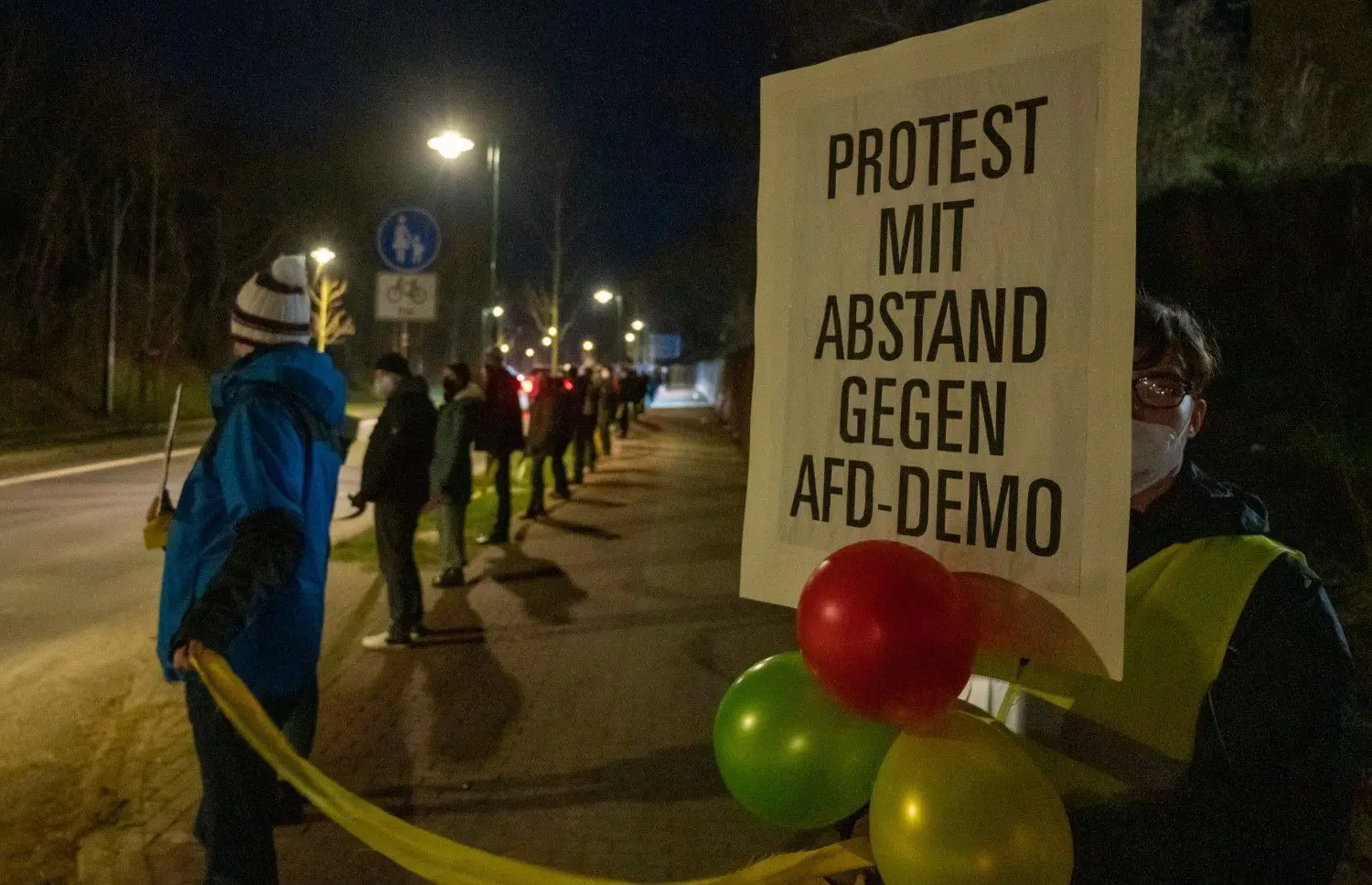 Bei einer Demonstration gegen eine Demonstration der AfD Brandenburg trägt ein Teilnehmer ein Plakat mit der Aufschrift ·"Protest mit Abstand gegen AfD-Demo"·.