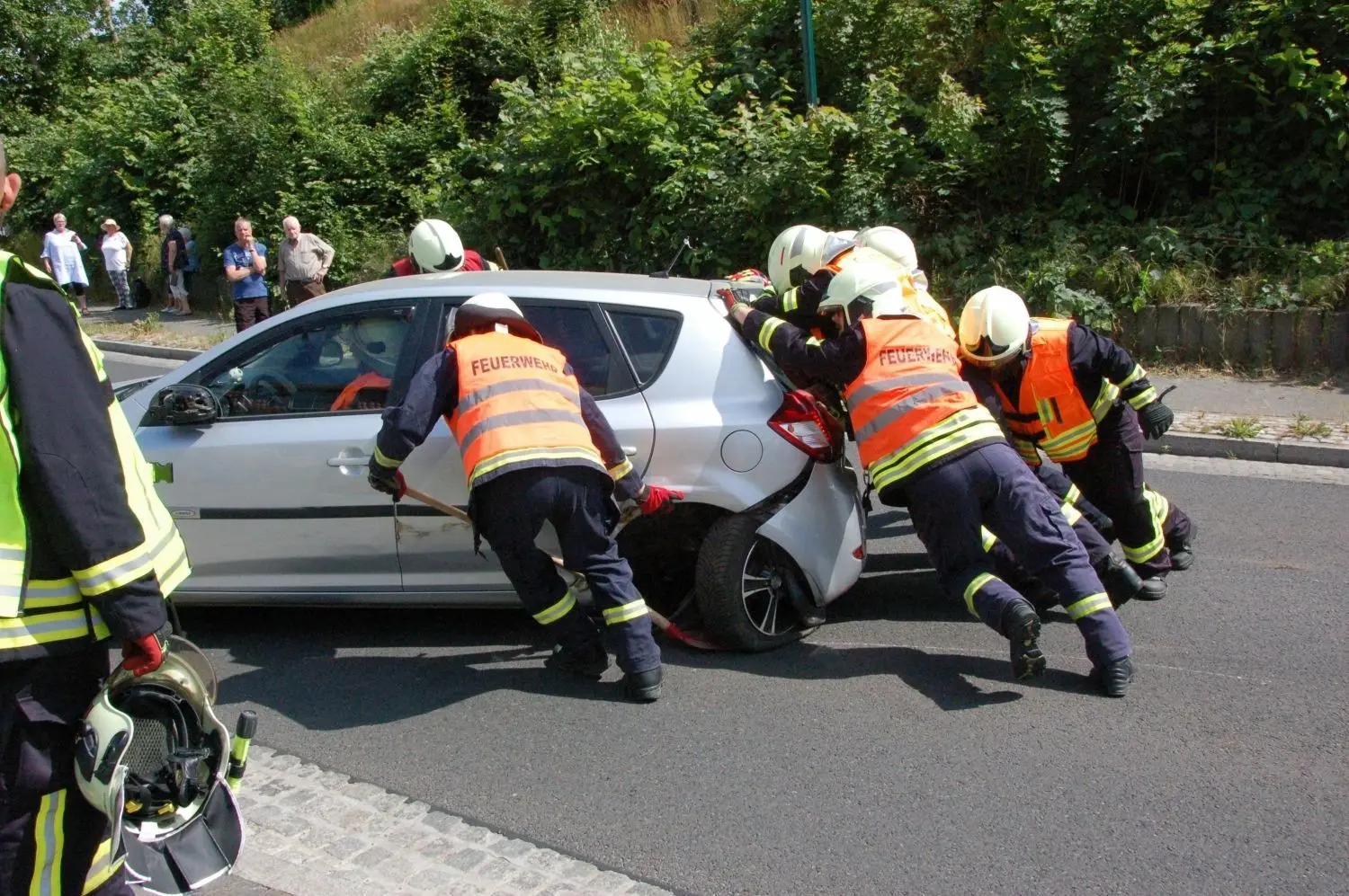 Achsbruch: Feuerwehrleute aus Falkenberg, Kruge/Gersdorf und Dannenberg schieben ein Unfallfahrzeug von der B167.