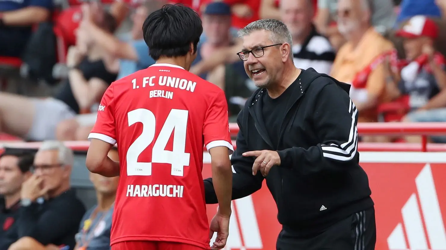 Trainer Urs Fischer (r.) von Union Berlin gibt Genki Haraguchi einige Tipps am Spielfeldrand.