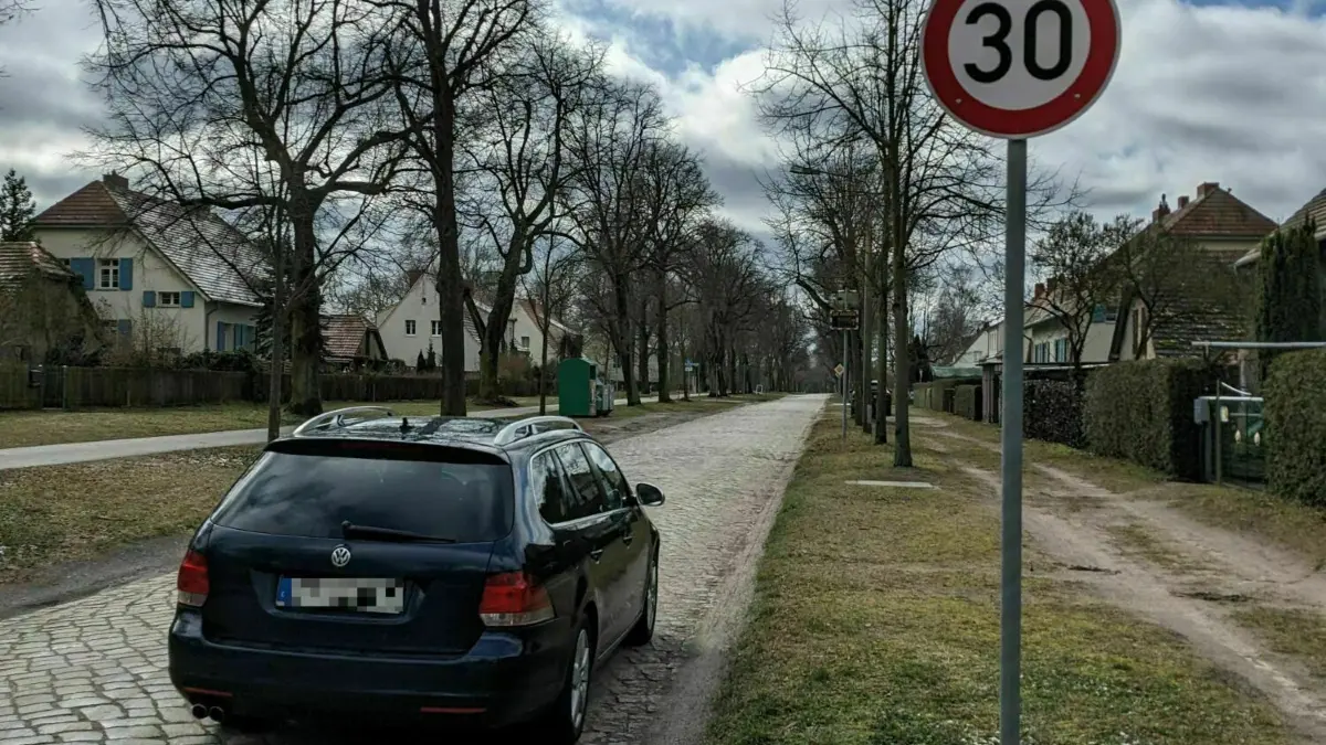 Die Einwohner von Hobrechtsfelde in Panketal leiden laut eigener Aussage unter massiver Lärmbelastung. Schuld daran seien Autofahrer, die insbesondere im morgendlichen und abendlichen Berufsverkehr mit überhöhten Geschwindigkeiten über die gepflasterte Dorfstraße fahren würden.
Dorfstraße in Hobrechtsfelde in Panketal, Auto fährt über Kopfsteinpflaster, 15.3.23