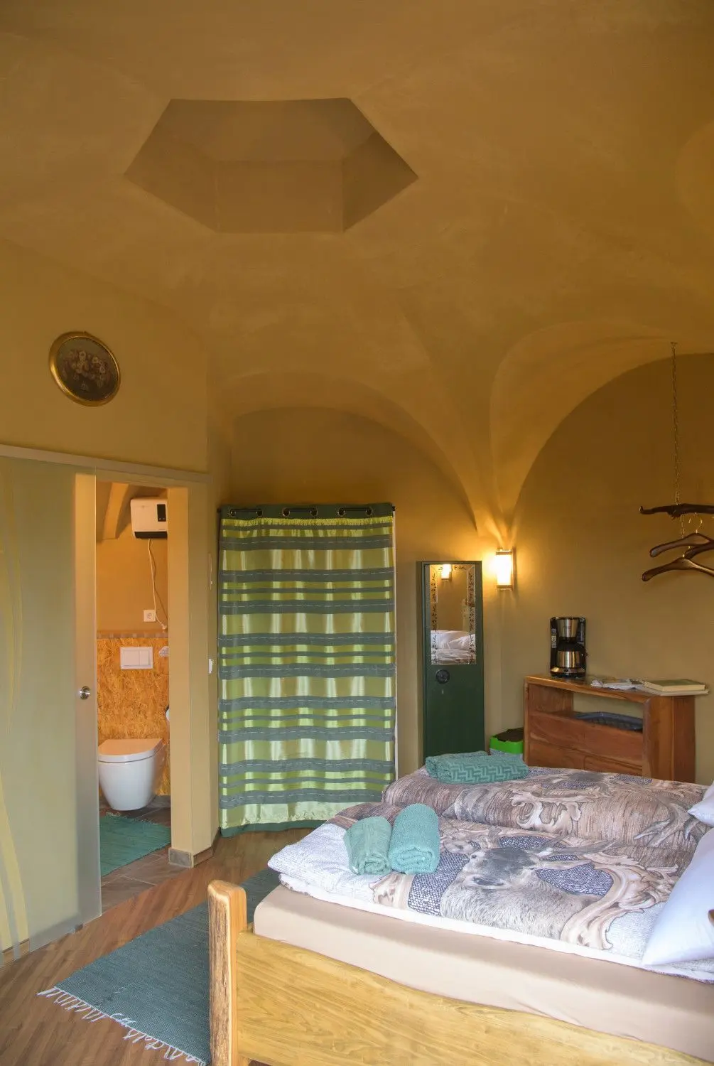 Das Appartment ·Schorfheide· des Erdhügelhauses mit einem Bett mit bedruckter Hirsch-Decke. Die Gewölberäume aus Beton im Garten von Familie Radow verbergen sich unter einer bis zu vier Meter dicken Erdschicht. Dadurch muss im Winter kaum geheizt werden, im Sommer bleibt es drinnen angenehm kühl.