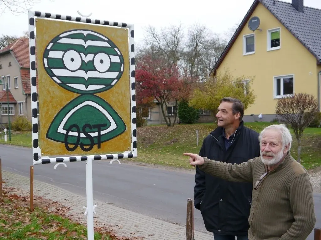 Ein Uhu oder was? Briesens Bürgermeister Jörg Bredow und Roland Rother (v.l.) vor einem der drei Schilder, die im östlichsten Wilmersdorf Deutschlands  Identität stiften sollen.