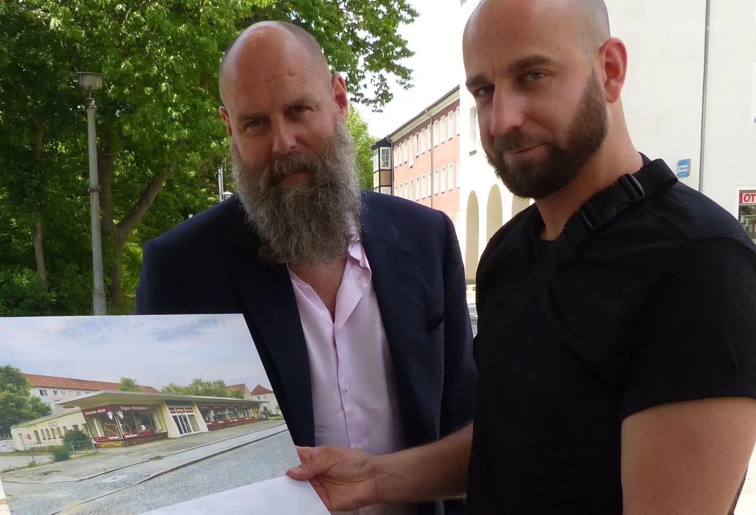 Unternehmer Holger Friedrich (l.) und Architekt Martin Maleschka schauen sich alte Fotos der Kaufhalle in der Saarlouiser Straße in Eisenhüttenstadt an. Friedrich ist der neue Eigentümer.