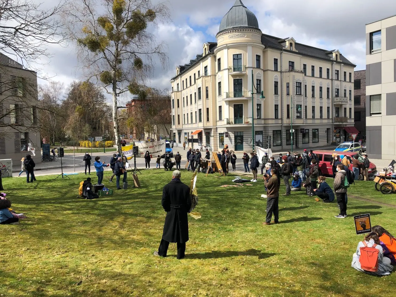 Protestversammlung auf der Wiese: Kundgebung gegen Abschiebung vor der Ausländerbehörde (Gebäude links) in Eberswalde.