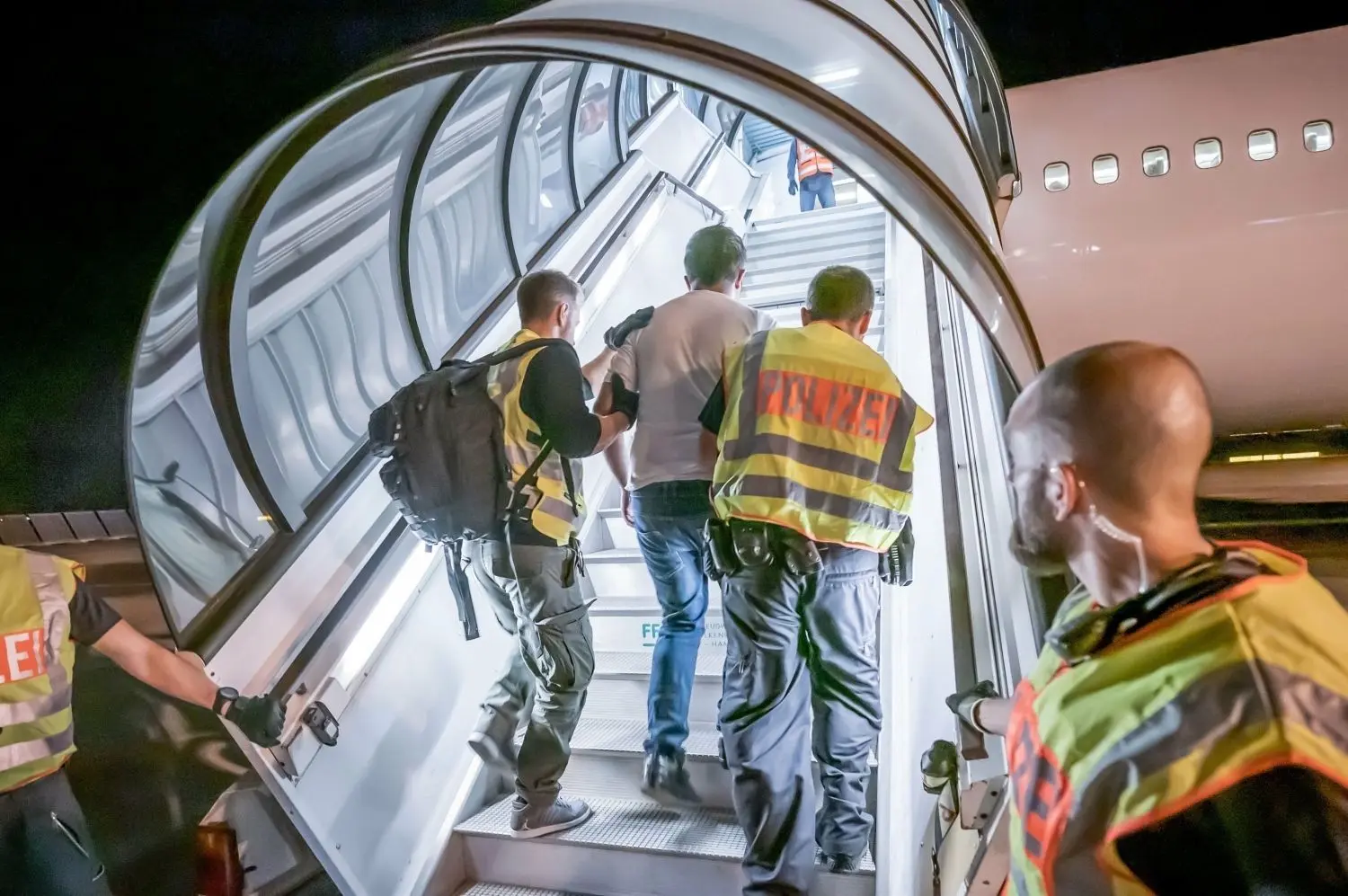 Polizeibeamte begleiten einen Afghanen auf dem Flughafen Leipzig-Halle in ein Charterflugzeug.  ⇥