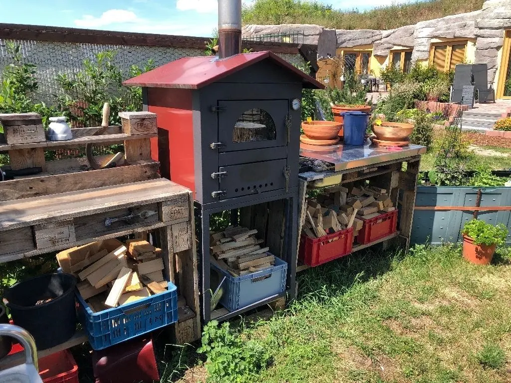Outdoorküche mit Holzbackofen: Feriengäste können sich an allem bedienen, was im Garten wächst – etwa an Kräutern und Salatköpfen.