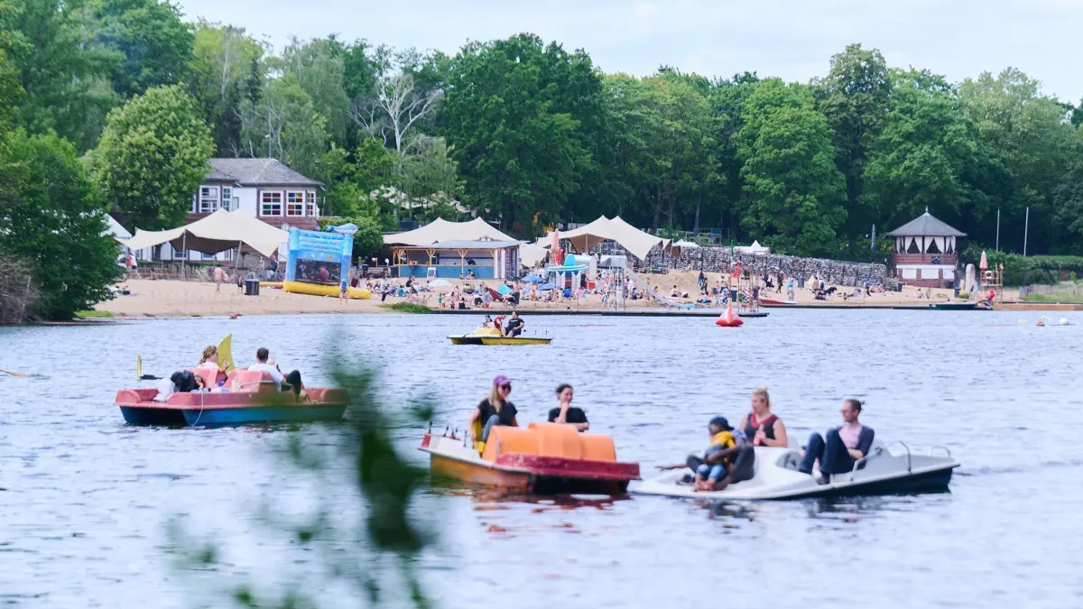Ausflüge: ARCHIV - 29.05.2023, Berlin: Tretboote sind vor dem Strandbad Plötzensee unterwegs. Das schöne Wetter am Pfingstmontag lockt viele Menschen an den See. (zu dpa: «Frühsommerliches Wetter lockt in Biergärten und zu Bootsverleihen») Foto: Annette Riedl/dpa +++ dpa-Bildfunk +++