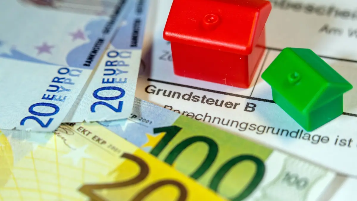 Grundsteuer: ARCHIV - 30.01.2019, Mecklenburg-Vorpommern, Schwerin: ILLUSTRATION - Ein Spielzeughaus und die Nachbildung von Euro-Geldscheinen liegen auf einem Abgabenbescheid für die Entrichtung der Grundsteuer. (zu dpa: «Trotz Länderkritik: Bund will Grundsteuer-Gesetz nicht ändern») Foto: Jens Büttner/dpa-Zentralbild/dpa +++ dpa-Bildfunk +++