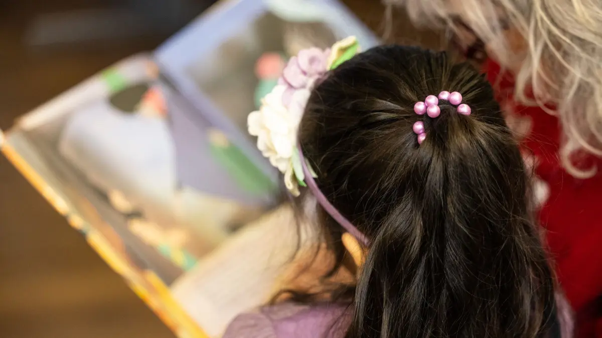 Start der Patenschaftskampagne für Familien: 24.04.2024, Berlin: Ein Kind ließt mit ihrer Patin ein Buch im Familienzentrum «RumBa». Mit dieser Kampagne sollen laut Veranstalter neue Ehrenamtliche gefunden und das Angebot für Familien gestärkt werden, die gezielt vor und direkt nach der Geburt eines Kindes durch Familienpaten unterstützt und entlastet würden. Das Projekt wird um 450 000 Euro gestärkt. Foto: Hannes P. Albert/dpa +++ dpa-Bildfunk +++