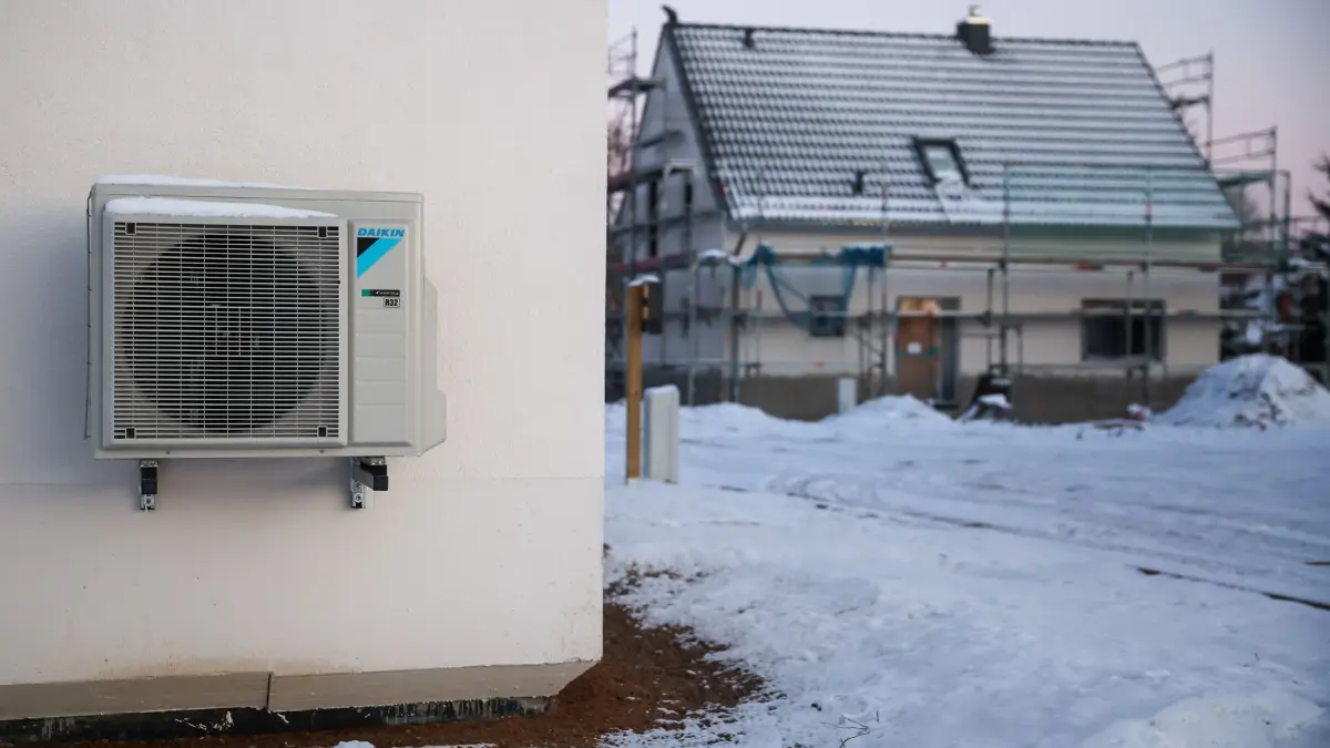 Haus mit Wärmepumpe: ARCHIV - 13.12.2022, Sachsen, Leipzig: Eine Luftwärmepumpe ist bei Schnee und Eis an einer Hauswand in einem neu entstehenden Einfamilienhausgebiet zu sehen. (zu dpa: «Großmakler: Preisverfall bei unsanierten Häusern gestoppt») Foto: Jan Woitas/dpa +++ dpa-Bildfunk +++