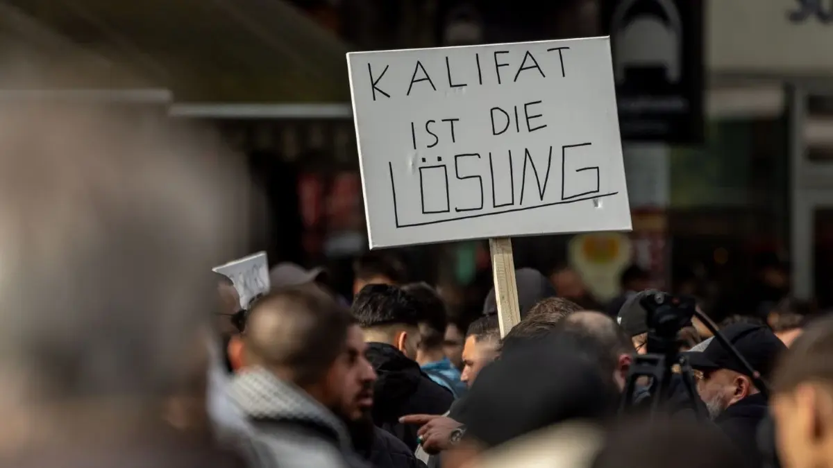 Teilnehmer einer Islamisten–Demo halten ein Plakat mit der Aufschrift „Kalifat ist die Lösung“ in die Höhe.
27.04.2024, Hamburg: Teilnehmer einer Islamisten-Demo halten ein Plakat mit der Aufschrift "Kalifat ist die Lösung" in die Höhe. Foto: Axel Heimken/dpa +++ dpa-Bildfunk +++