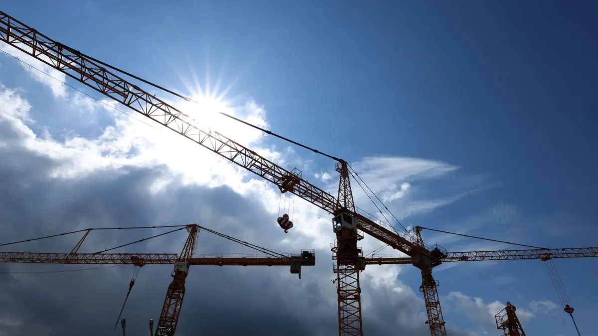 Baukräne: ARCHIV - 24.04.2024, Bayern, Mindelheim: Baukräne eines Kranservice stehen im Gegenlicht. Die Stimmung in der deutschen Wirtschaft hat sich im April erneut verbessert. (zu dpa: «BIHK: Sinkflug der bayerischen Wirtschaft gestoppt») Foto: Karl-Josef Hildenbrand/dpa +++ dpa-Bildfunk +++