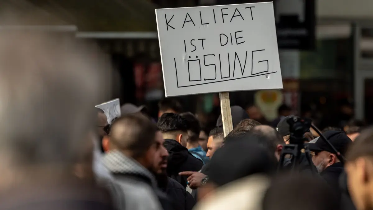 Demonstration der islamistischen Szene in Hamburg: ARCHIV - 27.04.2024, Hamburg: Teilnehmer einer Islamisten-Demo halten ein Plakat mit der Aufschrift „Kalifat ist die Lösung“ in die Höhe. (zu dpa: «Islamisten-Demos: Tschentscher stellt sich hinter Versammlungsbehörde») Foto: Axel Heimken/dpa +++ dpa-Bildfunk +++