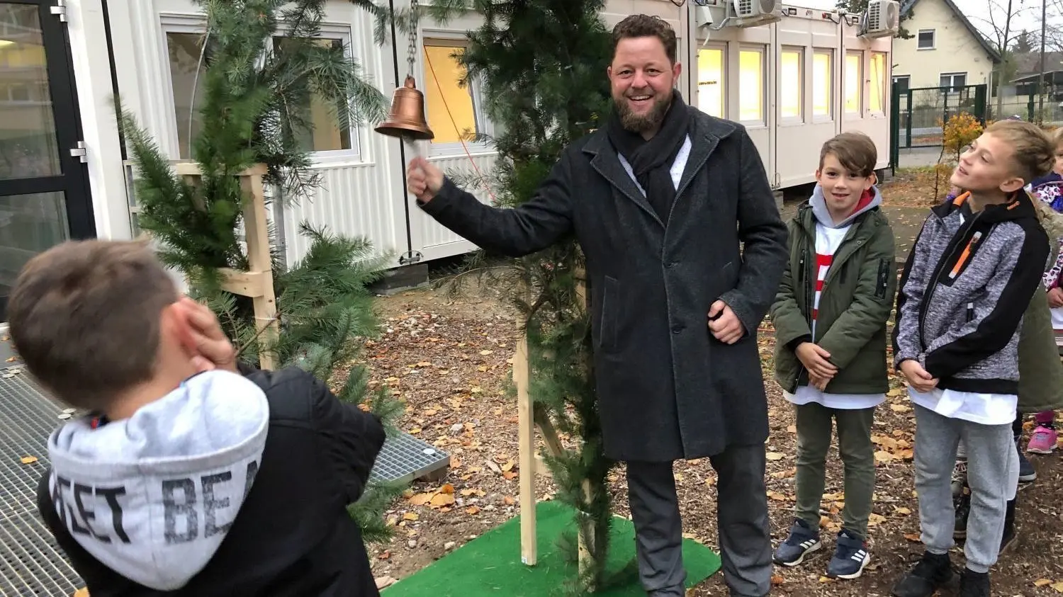 Kremmens Bürgermeister Sebastian Busse läutet zur ersten Stunde in der Container-Klasse der Goethe-Grundschule.