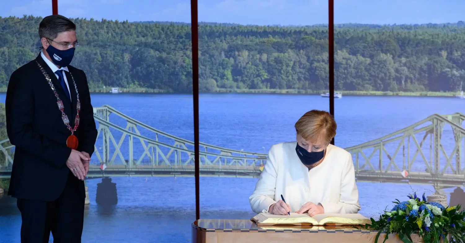 Bundeskanzlerin Angela Merkel (CDU) schreibt sich nach dem Festakt zum 30. Jahrestag der Deutschen Einheit in der Metropolishalle in das Goldene Buch der Stadt ein. Links steht Potsdams Oberbürgermeister Mike Schubert (SPD).