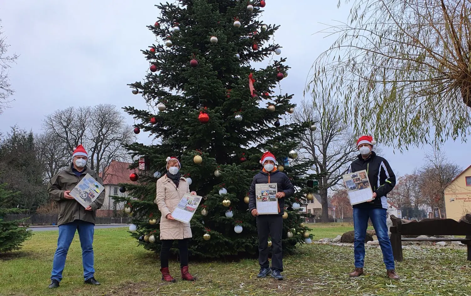 Jochen Schröter, Cathleen Wunderlich, Michael Jur und Andreas Reichert (v.l.) präsentieren den Kalender "675 Jahre Tauche" für das Jahr 2021 vor dem Weihnachtsbaum in Tauche. Der Erlös aus dem Verkauf soll zur Finanzierung der Jubiläumsfeier beitragen.