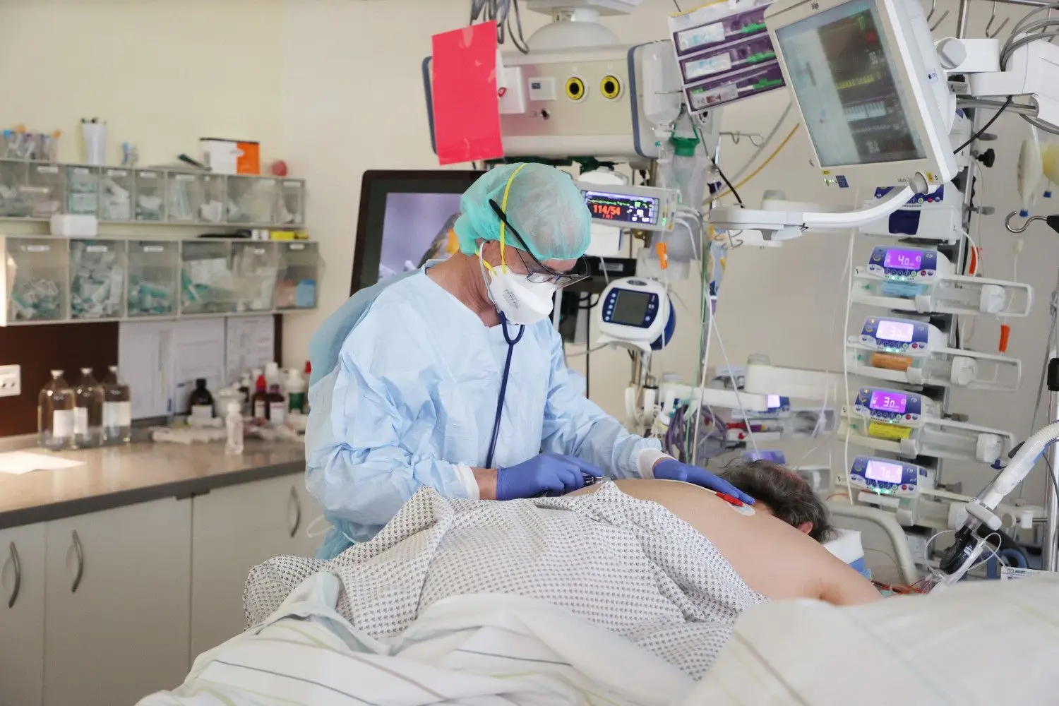 Ein Arzt untersucht einen Patienten auf einer Covid-19-Intensivstation. Wie stellen sich Krankenhäuser in Brandenburg und Berlin auf die Omikron-Welle ein? (Symbolbild)