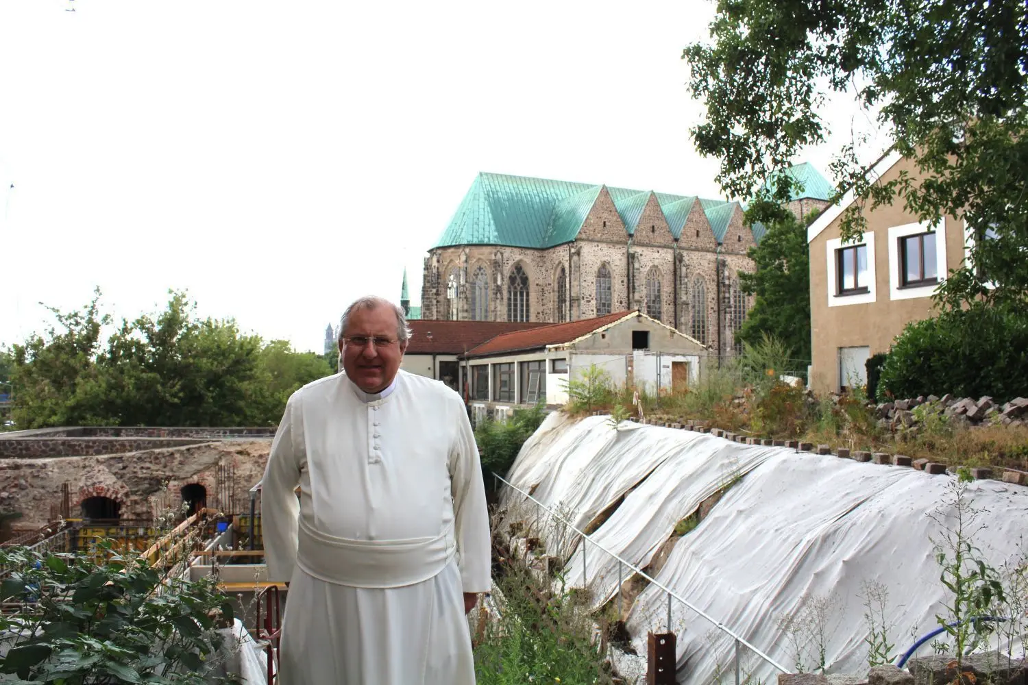 Ein Projekt für die Zukunft: Pater Clemens Dölken vor der katholischen Universitätskirche St. Petri in Magdeburg, links daneben die Klosterbaustelle der Ökomenischen Höfe.