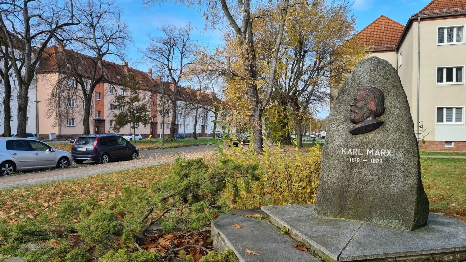 Die Karl-Marx-Straße im Herbst 2021 mit dem 1969 aufgestellten Gedenkstein für den Namensgeber.