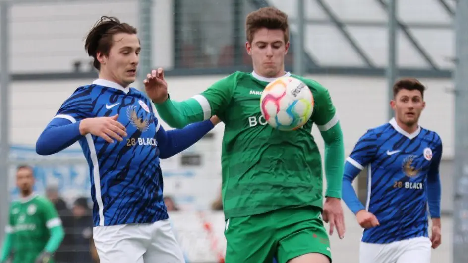 Kommen zum FSV Union Fürstenwalde im Durchschnitt fast 200 Zuschauer, so müssen im Auswärtsspiel beim Oberliga-Tabellenführer FC Hansa Rostock U23 die Fans hinter dem Metallzaun bleiben. Hier eine Szene aus dem Spiel im Februar mit John Gruber (in Grün), der das Leder vor Cosmo Syrbe behauptete.