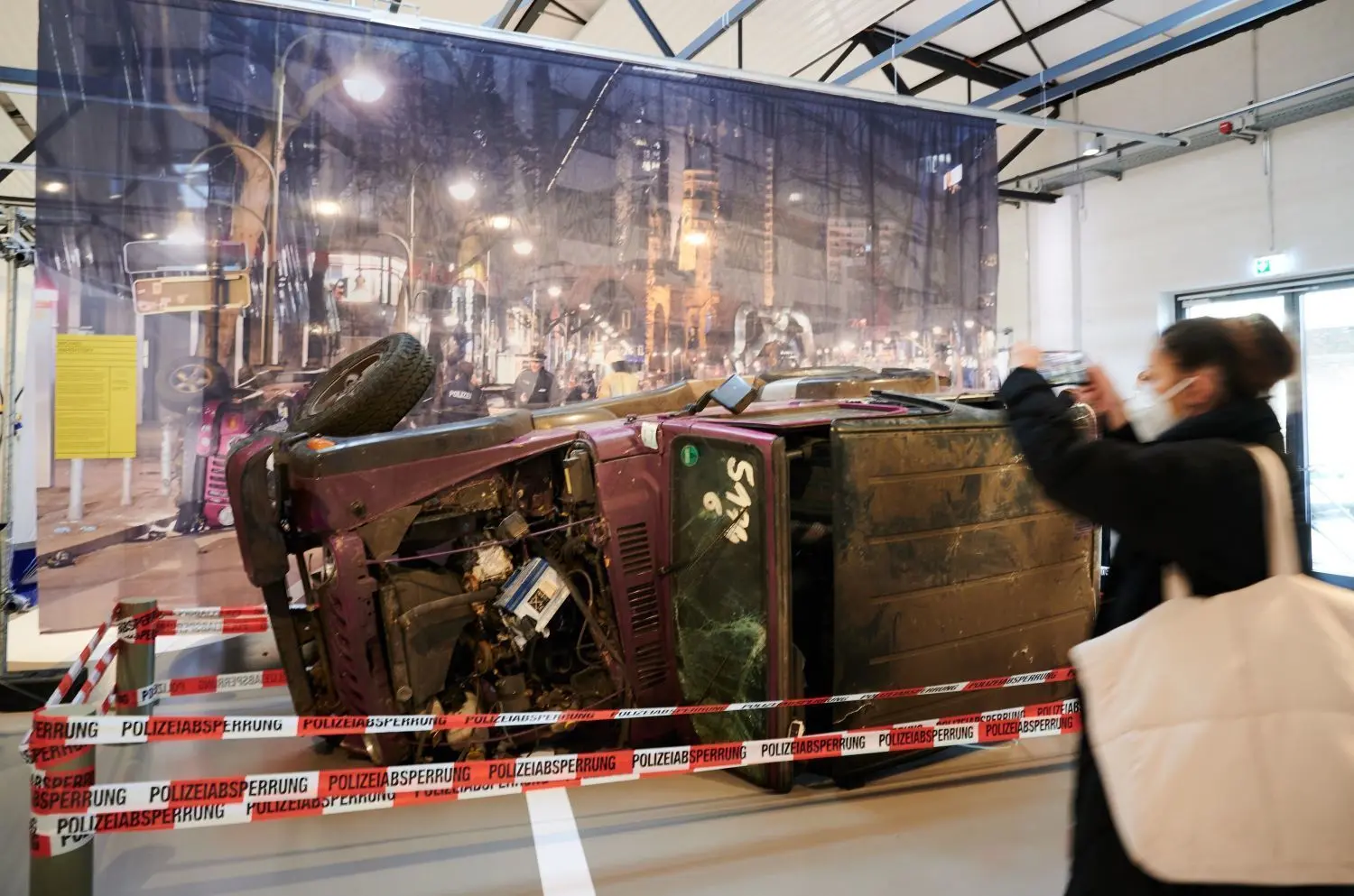 Gewagtes Exponat: Eine Frau fotografiert mit ihrem Handy in der Ausstellung „Wahnsinn – Illegale Autorennen“ im Berliner Technikmuseum den zerstörten Jeep von Michael Warshitsky, der 2016 Opfer der Ku’damm-Raser wurde.