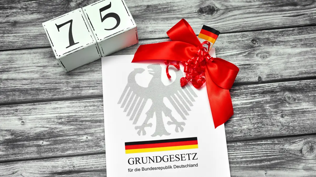 75 jahre Grundgesetz — Symbolfoto: Augsburg, Bavaria, Germany - May 21, 2024: The Basic Law of the Federal Republic of Germany turns 75. The Basic Law book with a red ribbon and date cube with the number 75 *** Das Grundgesetz der Bundesrepublik Deutschland wird 75 Jahre alt. Das Grundgesetz Buch mit einer roten Schleife und Datum Würfel mit der Zahl 75 / 210524