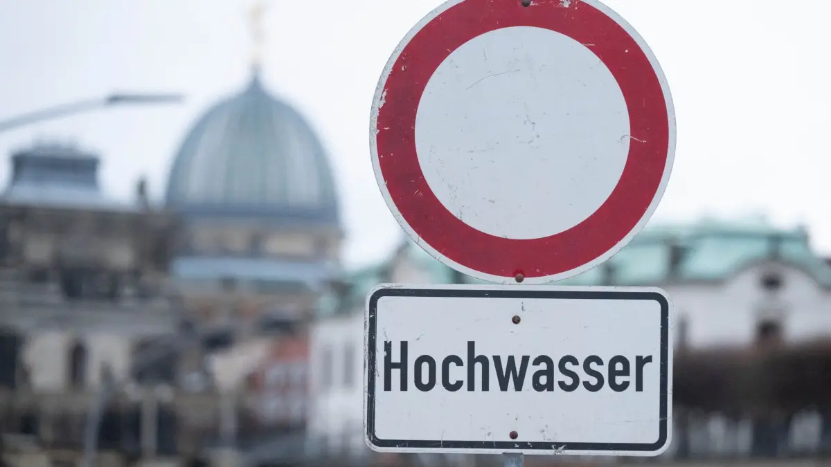 Hochwasser in Sachsen: ARCHIV - 25.12.2023, Sachsen, Dresden: Ein Schild mit der Aufschrift „Hochwasser“ steht am Terrassenufer. (zu dpa: «Weniger Versicherungsschäden in Sachsen durch Wetterextreme») Foto: Sebastian Kahnert/dpa +++ dpa-Bildfunk +++