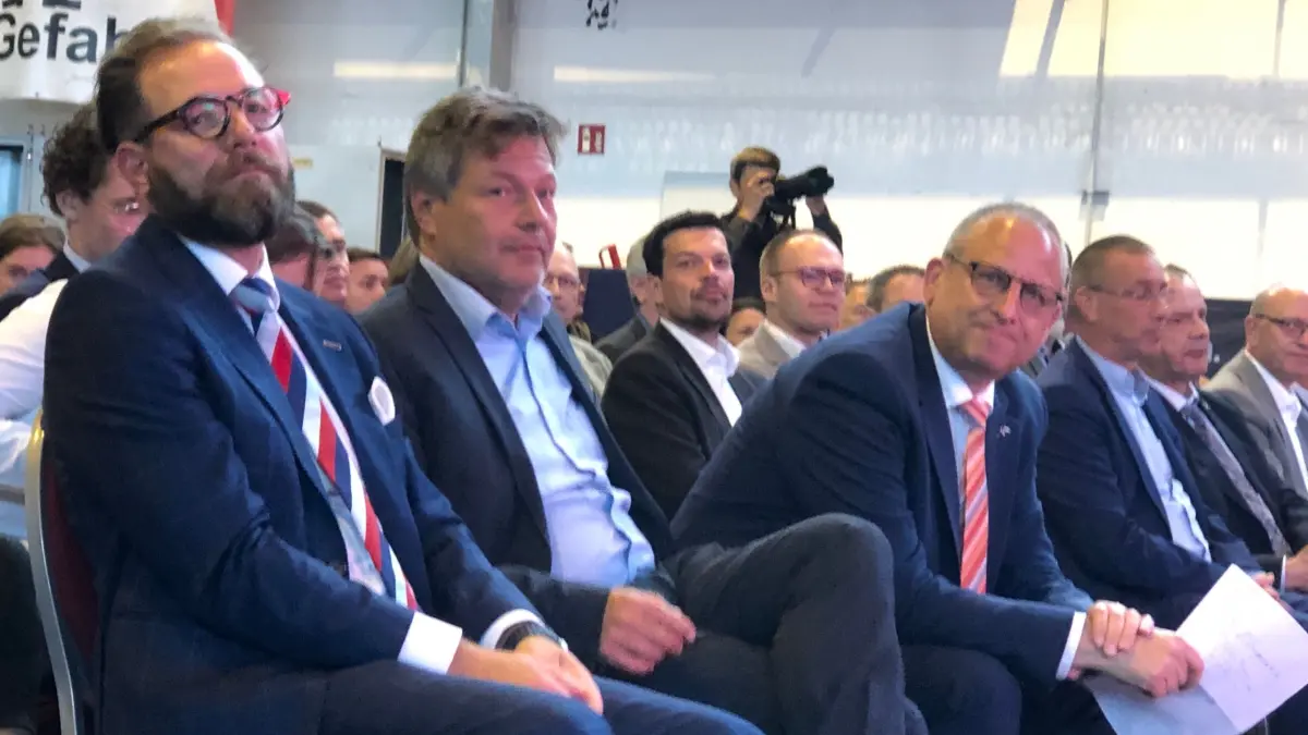 Robert Habeck in Eisenhüttenstadt. Rechts neben ihm sitzt Thomas Bünger, CEO von ArcelorMittal Eisenhüttenstadt und Bremen. Links vom Minister sitzt André Körner, Country Manager bei ArcelorMittal Germany.