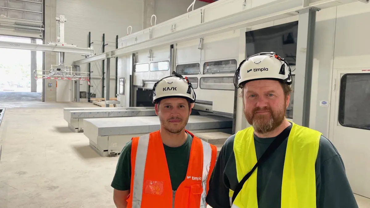 In der Timpla-Werkhalle stehen Business Development-Chef Philipp Nickl (l.) und Sprecher Sven Schwartz vor der haushohen Reichenbacher-Maschine, die Rohplatten vollautomatisch zuschneiden, bohren und fräsen kann.