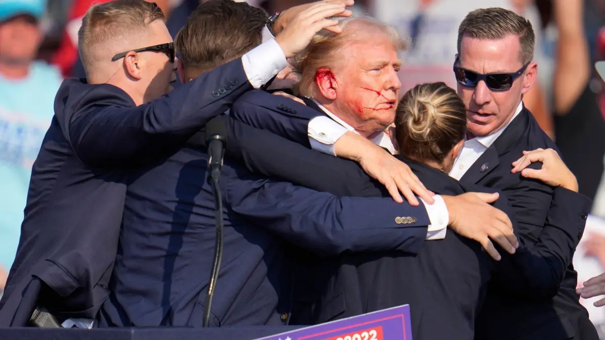 Wahlkampf in den USA - Trump in Butler: 14.07.2024, USA, Butler: Der republikanische Präsidentschaftsbewerberund frühere US-Präsident Donald Trump wird von Agenten des US-Geheimdienstes Secret Service umringt, als ihm bei einer Wahlkampfveranstaltung von der Bühne geholfen wird. Trump wurde während des Wahlkampfes attackiert. Auf Videoaufnahmen der Veranstaltung in der Stadt Butler waren Knallgeräusche zu hören. Trump fasste sich daraufhin ans Ohr und duckte sich dann weg. Sicherheitspersonal rannte auf die Bühne und schirmte ihn ab. Foto: Gene J. Puskar/AP/dpa +++ dpa-Bildfunk +++