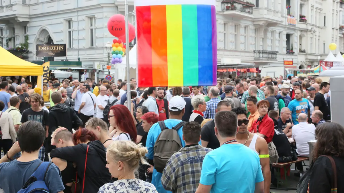 Dicht gedrängt gehen die Besucher des schwul-lesbischen Straßenfestes in Berlin an einer Regenbogen-Fahne vorbei. Das Stadtfest, das jährlich eine Woche vor dem Christopher Street Day (CSD) im Stadtteil Schöneberg feiert am Wochenende 20./21. Juli 2024 sein 30. Jähriges Jubiläum.