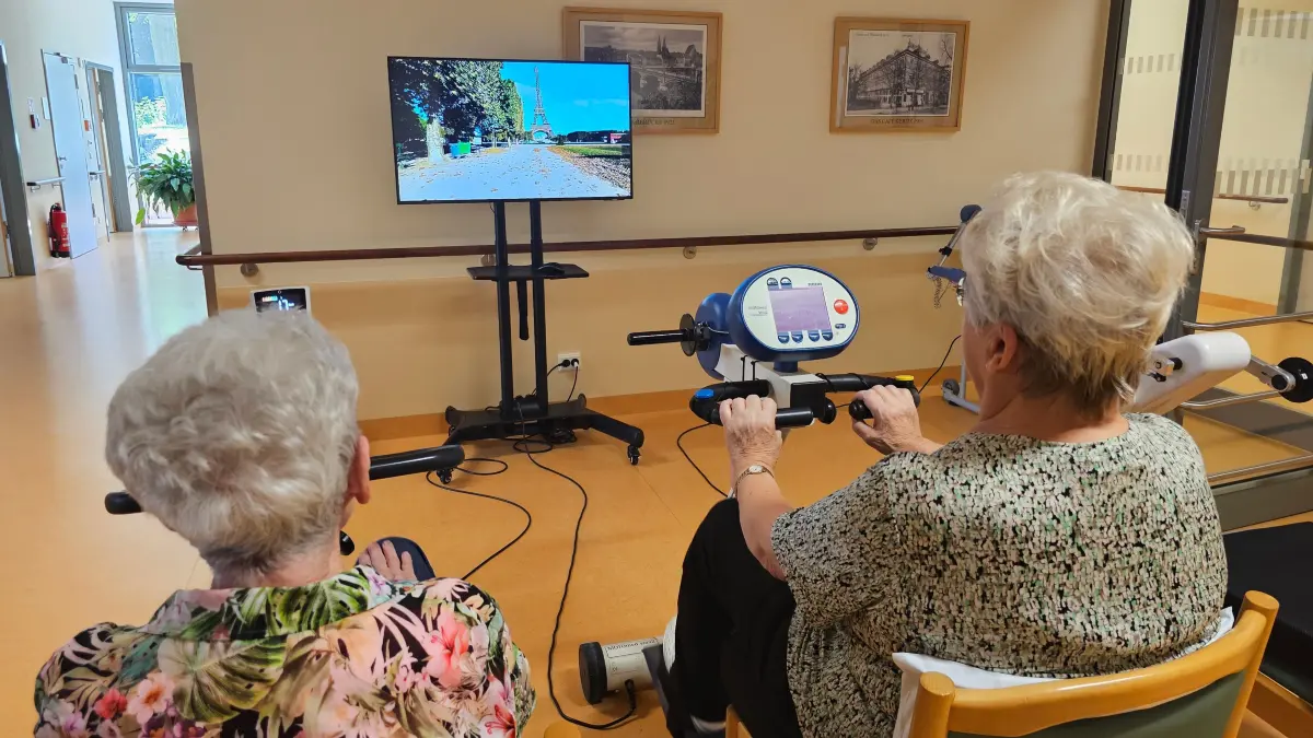 Virtuelle Radtour: Zwei Patientinnen der Geriatrischen Tagesklinik in Frankfurt (Oder) fahren auf dem Fahrrad-Ergometer scheinbar durch Paris.