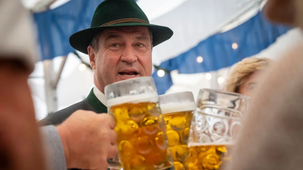 Chiemgauer Gaufest 2024: 28.07.2024, Bayern, Aschau Im Chiemgau: Markus Söder (CSU), Ministerpräsident von Bayern, stößt während dem Gaufest des Chiemgau Alpenverbands 2024 mit einem Bierkrug an. Angekündigt sind rund 5000 Teilnehmer und über 40 Festwagen. Foto: Peter Kneffel/dpa +++ dpa-Bildfunk +++