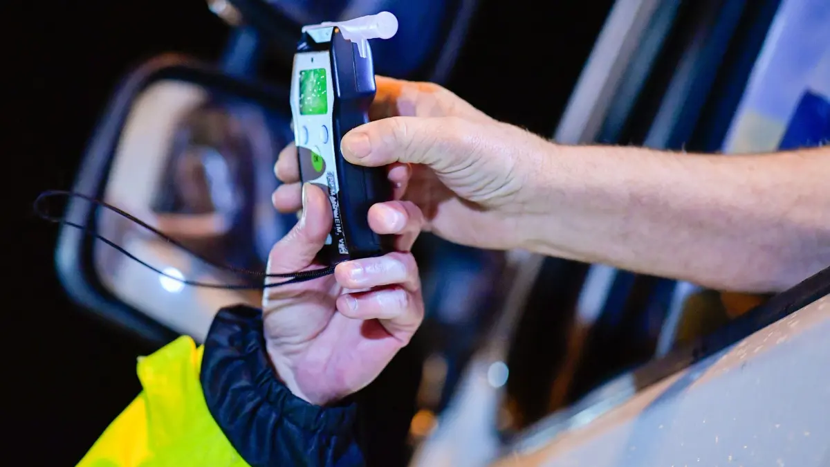 Alkoholkontrollen auf Autobahnraststätten - Symbolbild: ARCHIV - 09.12.2018, Baden-Württemberg, Sinsheim: Ein Polizist reicht einem Lastwagenfahrer ein Alkoholmessgerät in die Fahrerkabine. (zu dpa: «Mit rund drei Promille am Lkw-Steuer - Unfall auf A5») Foto: Uwe Anspach/dpa +++ dpa-Bildfunk +++