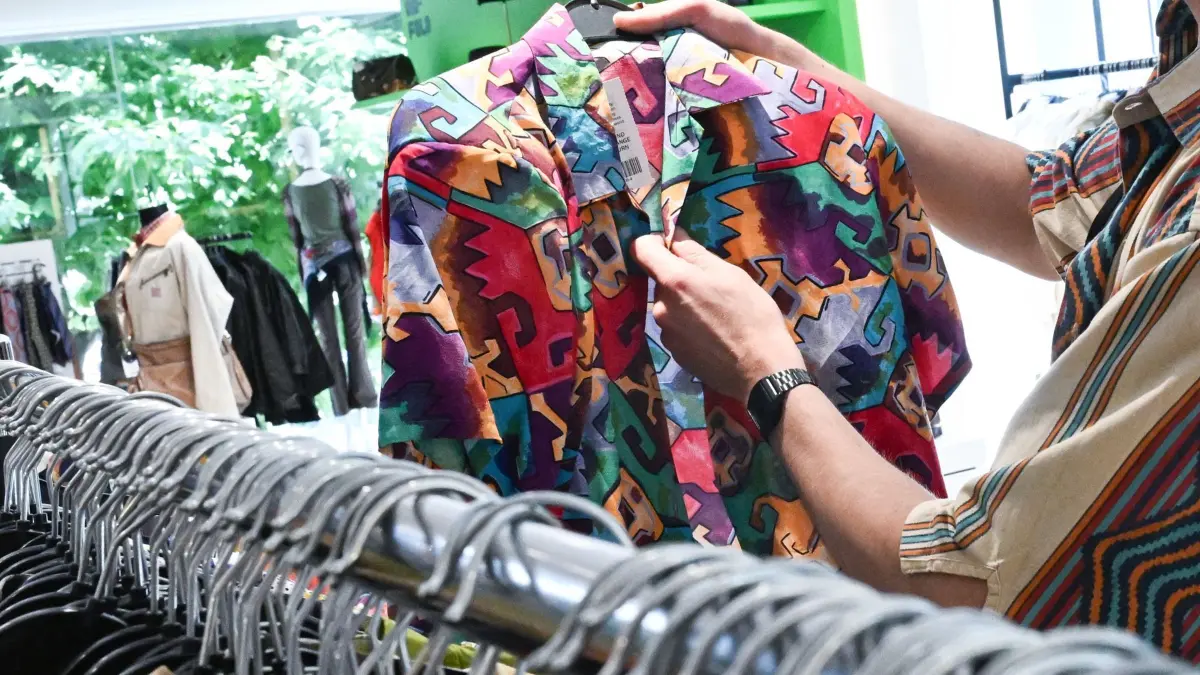 ARCHIV - 11.07.2024, Baden-Württemberg, Stuttgart: Ein Mitarbeiter sortiert in dem Modeladen für Second Hand Bekleidung PICKNWEIGHT un-fold Stuttgart, Kleidung. In dem Laden werden gebrauchte Bekleidungsstücke nach Kilogramm verkauft. (zu dpa: «Von Trödel zu Trend: Secondhand-Markt boomt mit Luxuswaren») Foto: Bernd Weißbrod/dpa +++ dpa-Bildfunk +++