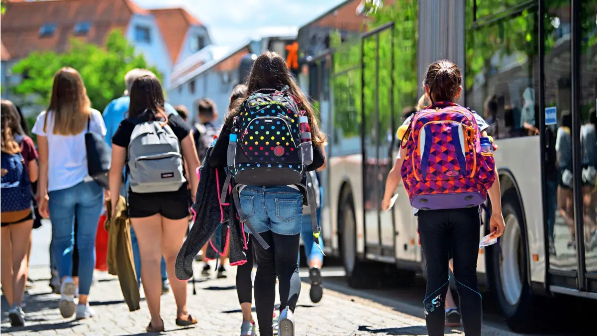 ARCHIV - 03.06.2019, Baden-Württemberg, Rottenburg am Neckar: Schülerinnen gehen an einer Bushaltestelle in der Innenstadt zu stehenden Bussen. (zu dpa: «Streit um kostenfreie Schülerbeförderung im Land») Foto: Marijan Murat/dpa +++ dpa-Bildfunk +++ | Verwendung weltweit