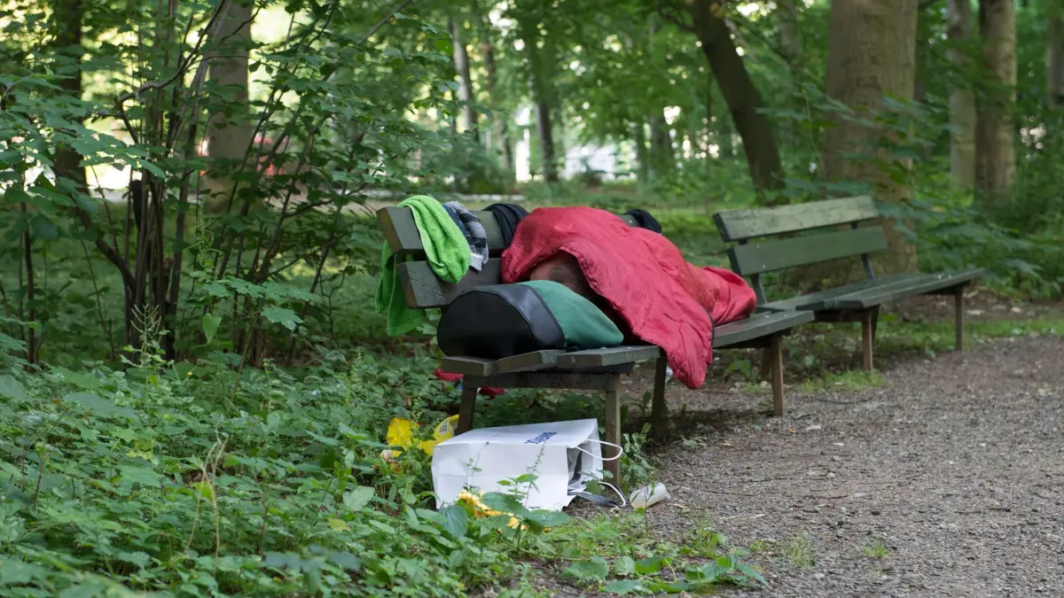 Obdachlosigkeit in Berlin: ARCHIV - 21.06.2017, Berlin: Ein Obdachloser liegt am frühen Morgen auf einer Bank im Tiergarten. Das Programm „Housing First“ mit dem Ziel, obdachlose Menschen dauerhaft in einer eigenen Wohnung zu versorgen, wurde in Berlin ausgebaut. Immer mehr Obdachlose finden dank des Programms eine eigene Wohnung. (zu dpa: «Wohnungen an 227 Obdachlose vermittelt») Foto: Paul Zinken/dpa +++ dpa-Bildfunk +++