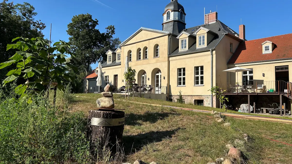 Frisch renoviert: das Gutshaus in Sonnenburg. Im Vordergrund der Stumpf der alten Tanne, die 2022 umstürzte, mit dem Hölderlin-Spruch „So komm, dass wir das Offene schauen“