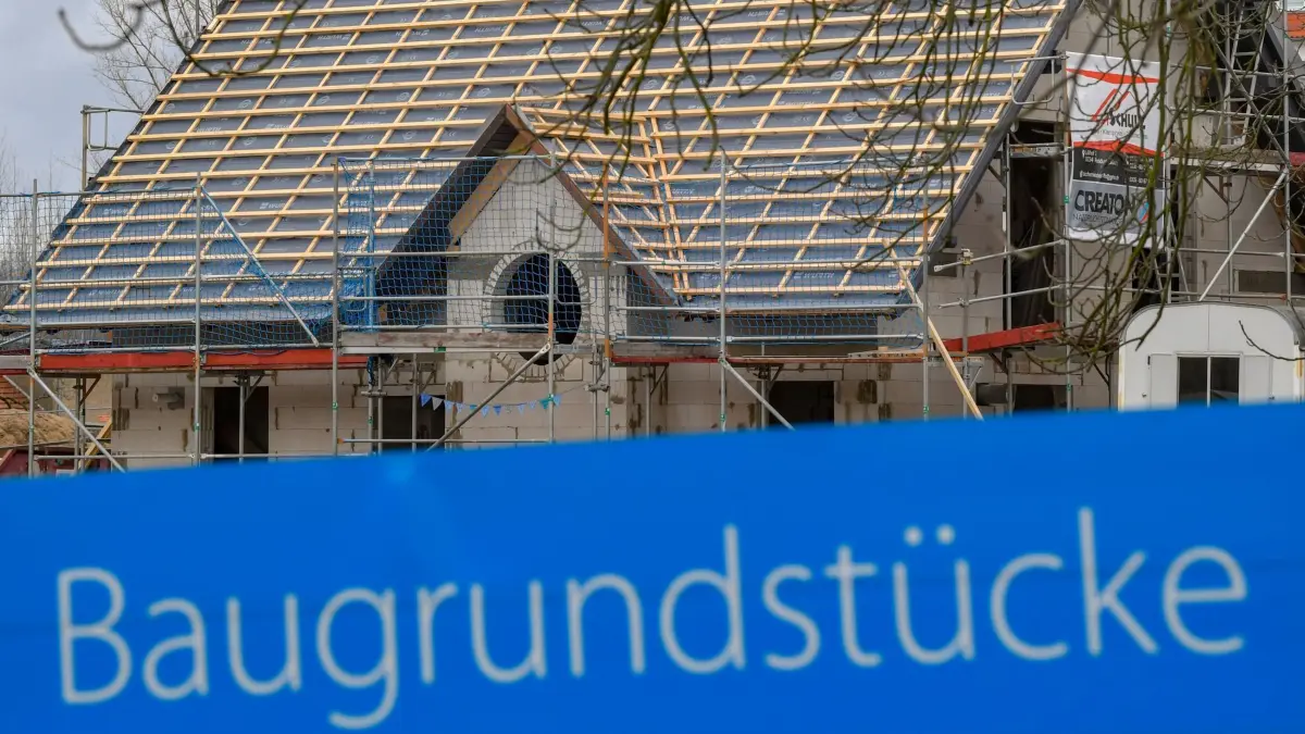 Bauland in Thüringen: ARCHIV - 10.01.2019, Brandenburg, Frankfurt (Oder): Ein Schild mit der Aufschrift «Baugrundstücke» steht am Rande eines Baufeldes mit einem Rohbau eines Eigenheimes. (zu dpa: «Preise für Thüringer Bauland in Jena am höchsten») Foto: Patrick Pleul/dpa-Zentralbild/dpa +++ dpa-Bildfunk +++
