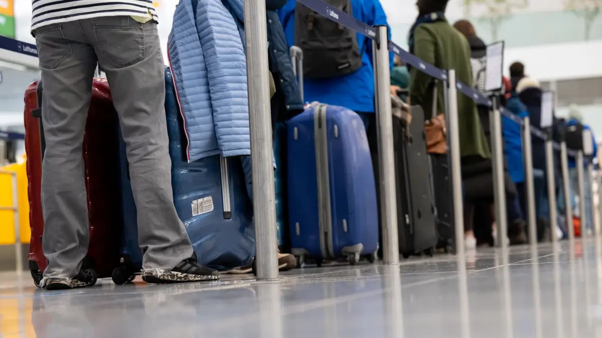 Passagiere am Flughafen: ARCHIV - 23.12.2022, Bayern, München: Passagiere stehen mit ihrem Gepäck an Check-in-Schaltern am Flughafen. (zu dpa: «Große bayerische Flughäfen ziehen positive Ferien-Bilanz») Foto: Sven Hoppe/dpa +++ dpa-Bildfunk +++