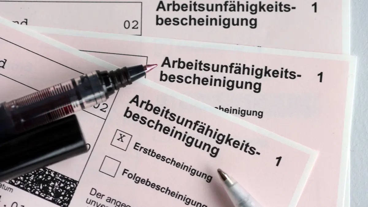 Krankenschein für Arbeitnehmer: ARCHIV - 14.01.2022, Schleswig-Holstein, Kiel: Stifte liegen auf den Arbeitsunfähigkeitsbescheinigungen für Arbeitnehmer im Falle einer Krankschreibung durch den Arzt. (zu dpa: «Lohnfortzahlung kostet Arbeitgeber 77 Milliarden Euro») Foto: Jens Büttner/dpa-Zentralbild/dpa +++ dpa-Bildfunk +++