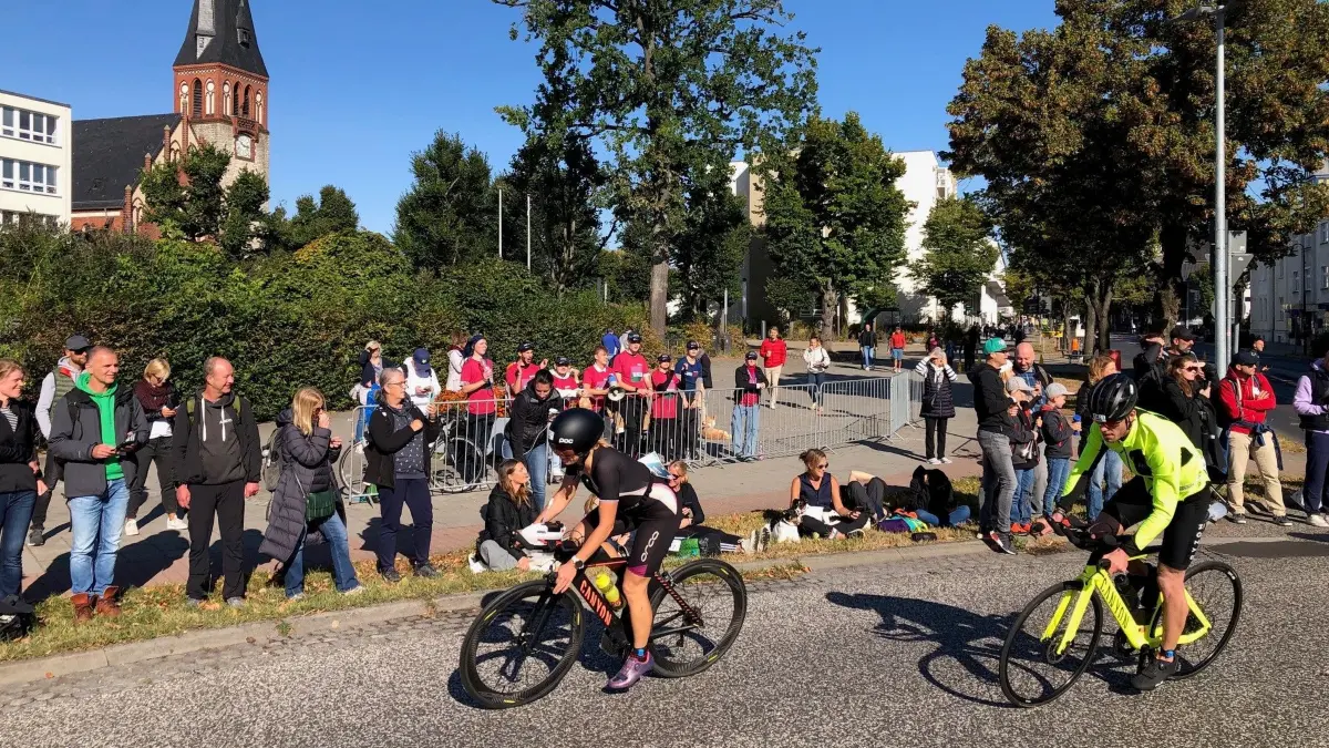 Ironman 2024 in Erkner: Am ovalen Kreisverkehr entlang der Friedrichstraße werden die Triathletinnen und Triathleten von zahlreichen Fans gefeiert.