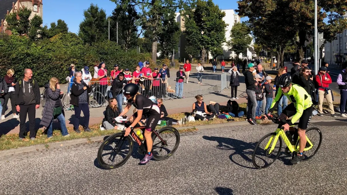 Ironman 2024 in Erkner: Am ovalen Kreisverkehr entlang der Friedrichstraße werden die Triathletinnen und Triathleten von zahlreichen Fans gefeiert.