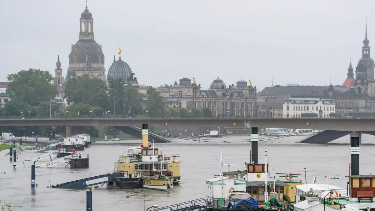Hochwasser in Sachsen: 16.09.2024, Sachsen, Dresden: Die Anleger für Schiffe der Sächsischen Dampfschifffahrt sind vom Hochwasser der Elbe umspült, im Hintergrund ist die Altstadtkulisse und die teileingestürzte Carolabrücke zu sehen. Foto: Robert Michael/dpa +++ dpa-Bildfunk +++