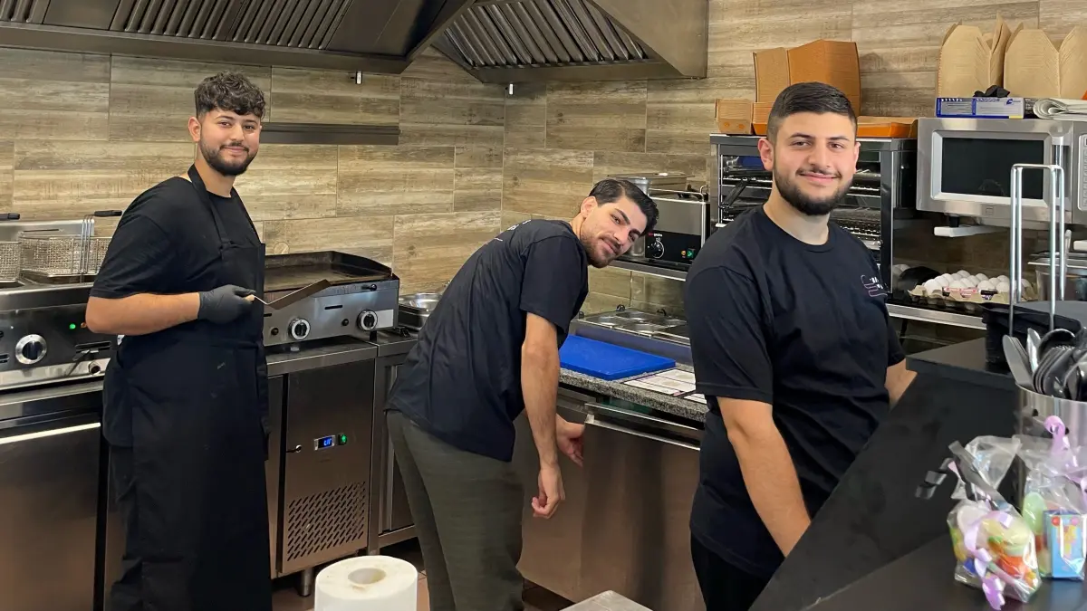 Drei von den fünf Oriental-Boys stehen in der Küche ihres neuen Burger-Ladens in Oranienburg. Was die fünf jungen Unternehmer auf die Beine gestellt haben und was es alles zu essen gibt.