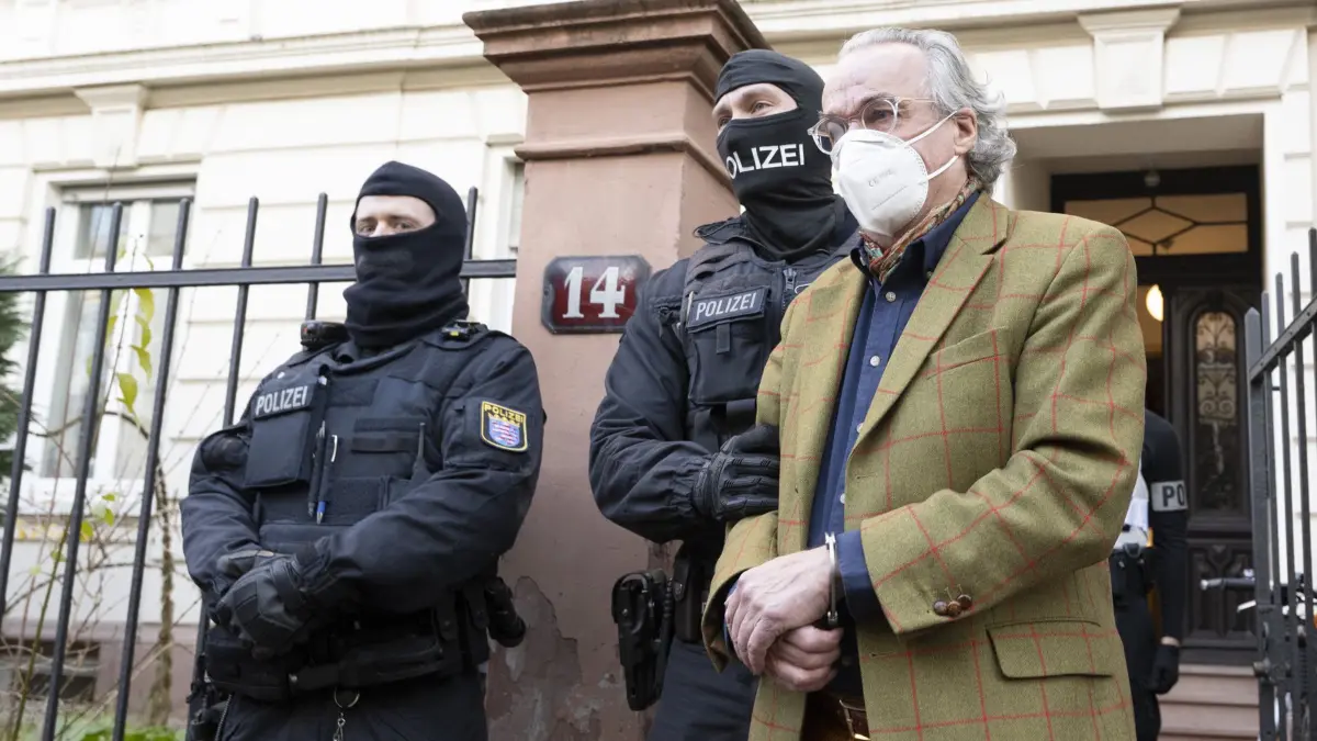 ARCHIV - 07.12.2022, Hessen, Frankfurt/Main: Bei einer Razzia gegen sogenannte «Reichsbürger» führen vermummte Polizisten, nach der Durchsuchung eines Hauses Heinrich XIII Prinz Reuß (r) zu einem Polizeifahrzeug. In einer eigens errichteten großen Halle am Stadtrand der Mainmetropole müssen sich ab Dienstag, 21. Mai die Rädelsführer der «Reichsbürger»-Gruppierung um Heinrich XIII. Prinz Reuß vor dem Oberlandesgericht wegen Terrorverdachts verantworten. (zu dpa: ««Reichsbürger»-Prozess in Frankfurt ist Herausforderung für die Justiz») Foto: Boris Roessler/dpa +++ dpa-Bildfunk +++