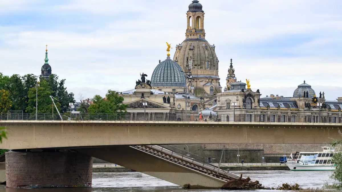 Nach Einsturz der Carolabrücke: 25.09.2024, Sachsen, Dresden: Brückenteile der teileingestürzten Carolabrücke liegen in der Elbe im Wasser, im Hintergrund ist die Altstadt mit der Frauenkirche zu sehen. Nachdem der Elbpegel aktuell unter 4,50 Meter gesunken ist, können die Abbrucharbeiten an den Teilen des Zuges C der Carolabrücke an der Altstädter Seite weiter vorbereitet werden. Die ersten Arbeiten starten heute. Foto: Robert Michael/dpa +++ dpa-Bildfunk +++