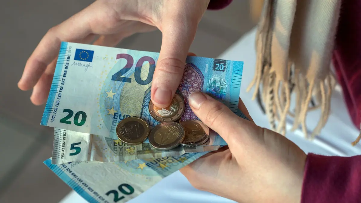 Taschengeld: ARCHIV - 20.12.2016, Mecklenburg-Vorpommern, Schwerin: ILLUSTRATION - Eine Jugendliche hält Euro-Banknoten und Geldmünzen. (gestelltes Foto). (zu dpa: «Vater sticht im Streit um Taschengeld auf Sohn ein - Urteil») Foto: Jens Büttner/dpa +++ dpa-Bildfunk +++