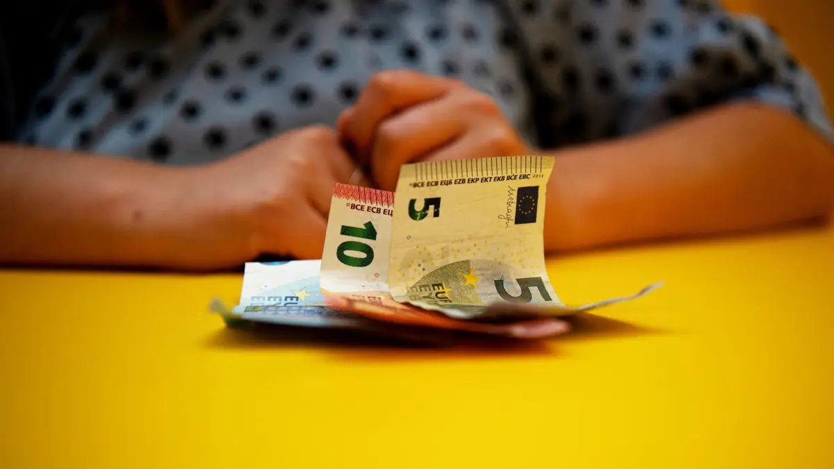 Bargeld liegt vor einer Frau auf einem Tisch: ILLUSTRATION - Damit Ihnen nicht nur ein Teil Ihrer Auszahlung bleibt: P-Konto-Inhaber, die mit Nachzahlungen von Sozialhilfen oder Renten rechnen, sollten rechtzeitig einen Freistellungsantrag dafür stellen. (zu dpa: «Wohngeld, Rente & Co: Vorsicht bei Nachzahlungen auf P-Konto») Foto: Bernd Diekjobst/dpa-tmn - Honorarfrei nur für Bezieher des dpa-Themendienstes +++ dpa-Themendienst +++